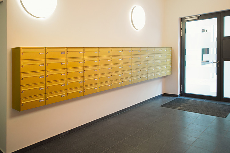 Briefkastenanlage in gelb als Aufputzversion im Eingangsbereich